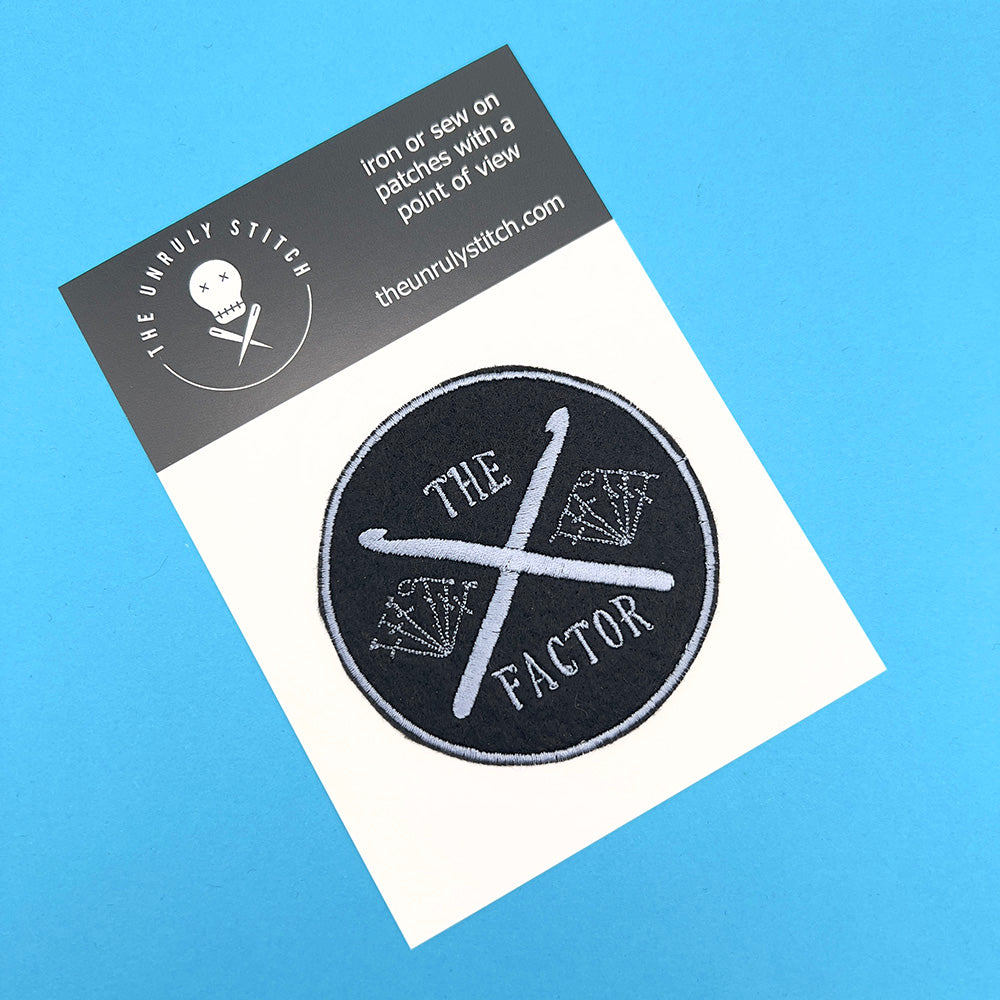 Branded postcard with embroidered felt patch featuring crossed crochet hooks with stitch symbols.