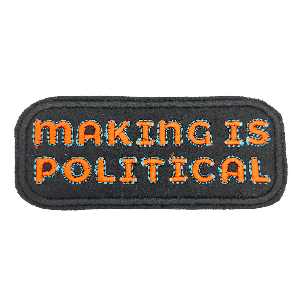 Close-up image: Close-up view of an embroidered felt patch with the text "Making is Political" in orange letters outlined in blue on a black background.