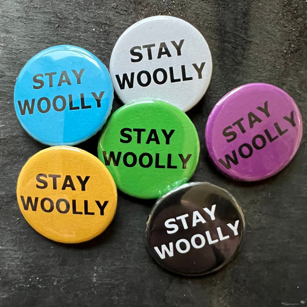 Six STAY WOOLLY pin badges in black, blue, pink, green, yellow, and white.