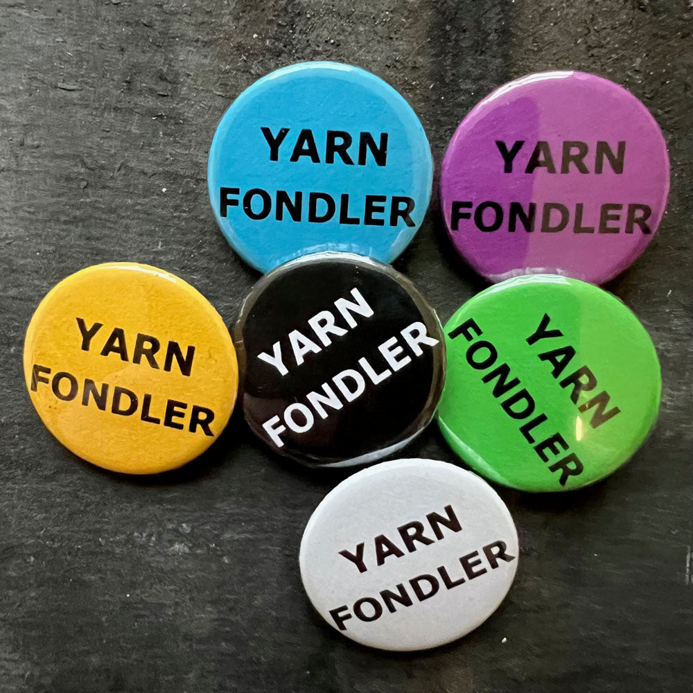 Six YARN FONDLER pin badges in black, blue, pink, green, yellow, and white.