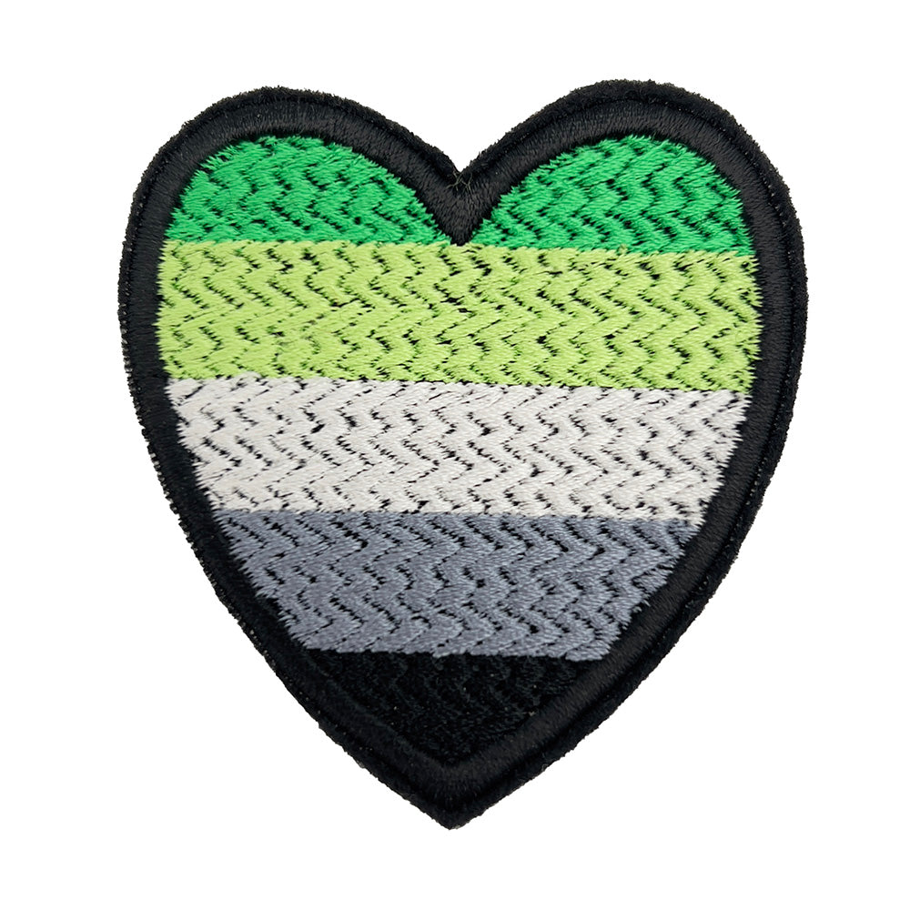 Close-up view of a heart-shaped embroidered felt patch featuring the Aromantic Pride flag colors in shades of green, white, gray, and black from The Unruly Stitch.