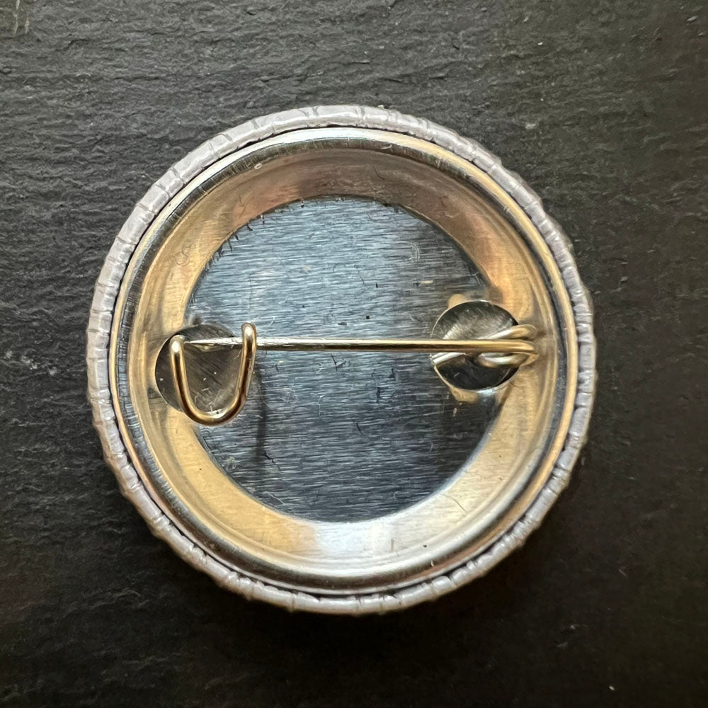 Back view of a pin badge showing the metal pin mechanism.