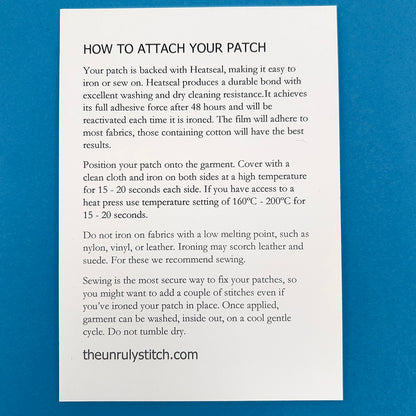 Back of postcard. A card titled 'HOW TO ATTACH YOUR PATCH' with detailed instructions on using Heatseal to iron or sew the patch onto garments, including recommended temperatures and tips for best results. The card is from theunrulystitch.com.