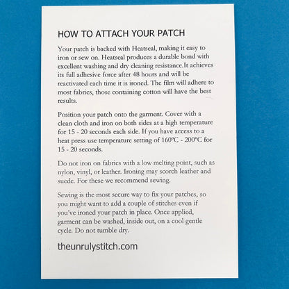 Back of postcard. A card titled 'HOW TO ATTACH YOUR PATCH' with detailed instructions on using Heatseal to iron or sew the patch onto garments, including recommended temperatures and tips for best results. The card is from theunrulystitch.com.