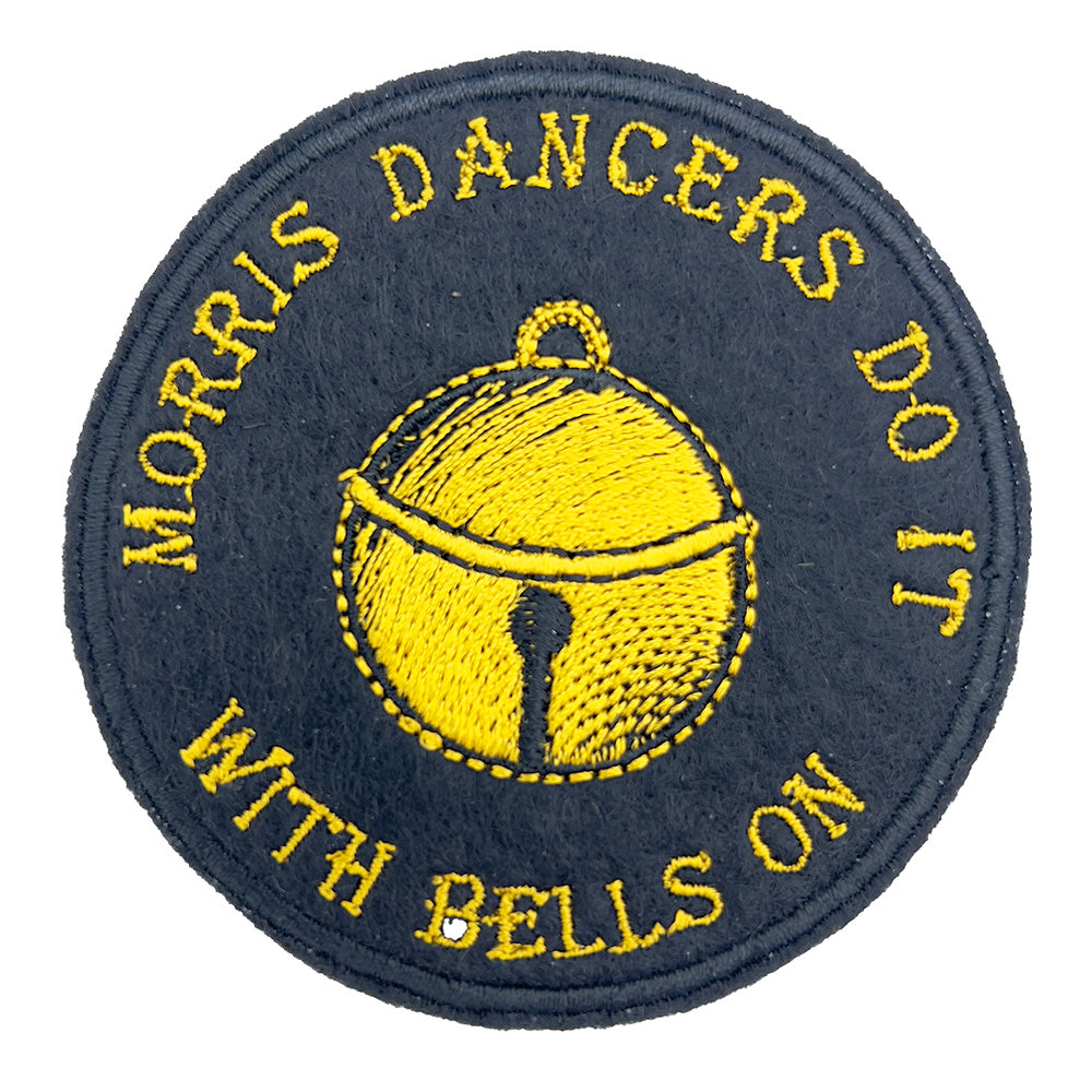 Close-up view of an embroidered felt patch featuring a yellow bell with black outline. The text around the bell reads, "Morris Dancers Do It With Bells On" in yellow embroidery on a black background.
