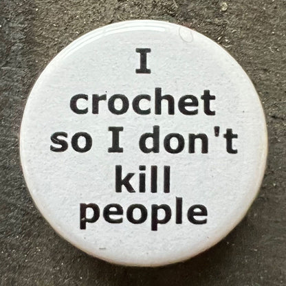Close-up of a white I crochet so I don't kill people pin badge with black text.