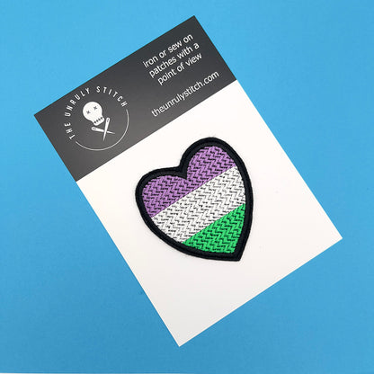 Gender queer pride flag heart-shaped embroidered felt patch displayed on a branded card with "The Unruly Stitch" logo. The patch features horizontal stripes in purple, white, and green.