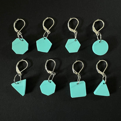 A set of geometric stitch markers in mint green perspex on jump rings, including circles, triangles, squares, pentagons, hexagons, and octagons, displayed on a black background.