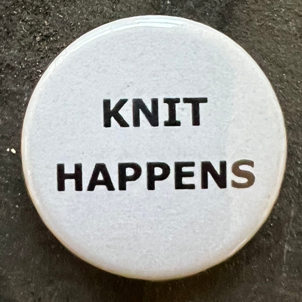  Close-up of a white KNIT HAPPENS pin badge with black text.