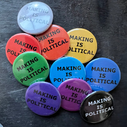 A group of nine colorful pin badges arranged on a dark surface. Each badge features the text "MAKING IS POLITICAL" in black. The badges come in various colors, including red, orange, yellow, green, blue, purple, black, and white.
