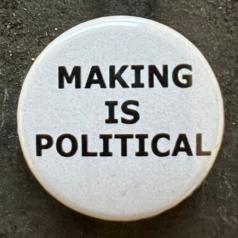 A close-up of a single pin badge with the text "MAKING IS POLITICAL" in black on a white background.