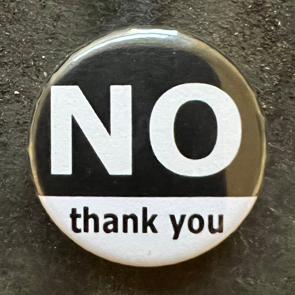 Close up of pin badge with text "NO thank you" No is in large capitals.