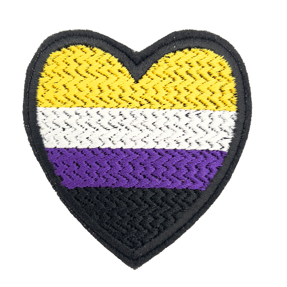 A close-up view of a heart-shaped embroidered felt patch featuring the non-binary pride flag colors: yellow, white, purple, and black stripes.