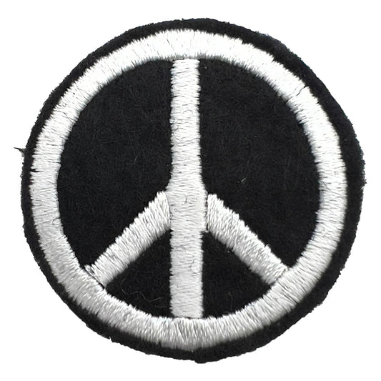 Close-up of a felt badge with an embroidered peace symbol in white threads on a black background, designed by The Unruly Stitch.