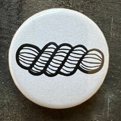 White pin badge with a black skein of yarn design.