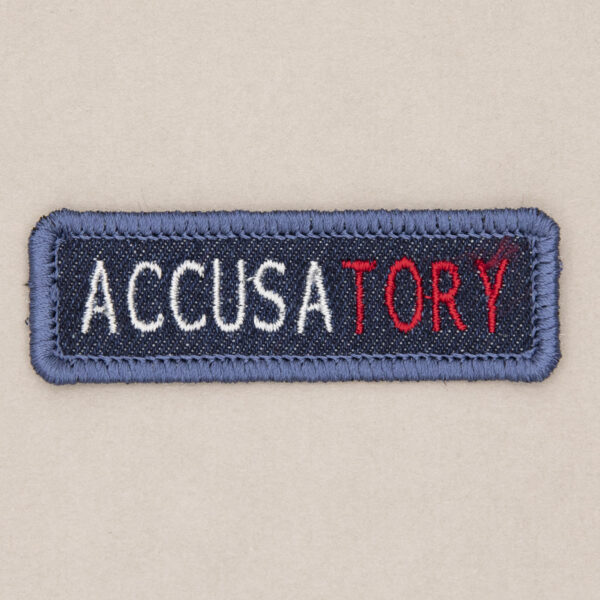 blue denim patch embroidered with the word ACCUSATORY