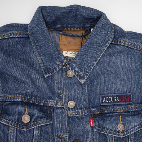 demin jacket with blue denim patch embroidered with the word ACCUSATORY
