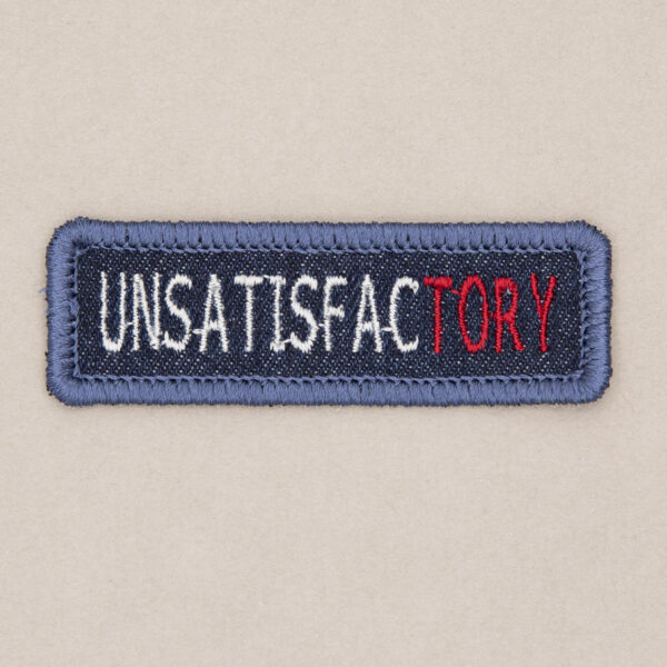blue denim patch embroidered with the word UNSATISFACTORY