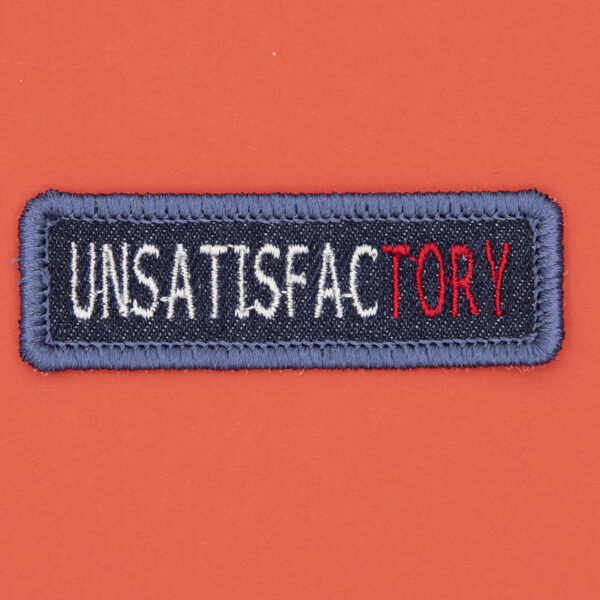 blue denim patch embroidered with the word UNSATISFACTORY