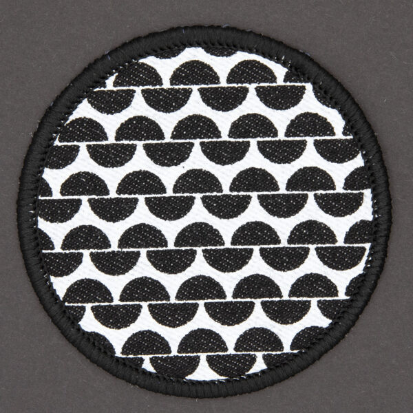 patch made from black denim screen printed with a garter stitch print and finished with an embroidered border