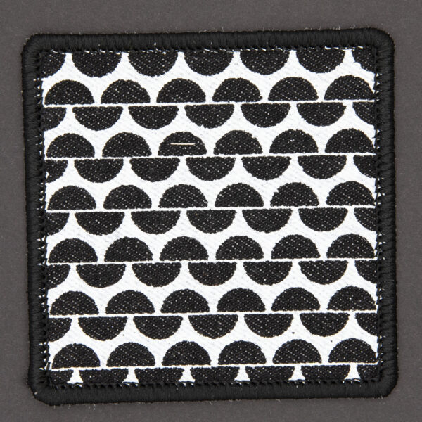 patch made from black denim screen printed with a garter stitch print and finished with an embroidered border