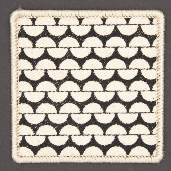 patch made from cream denim screen printed with a garter stitch print and finished with an embroidered border