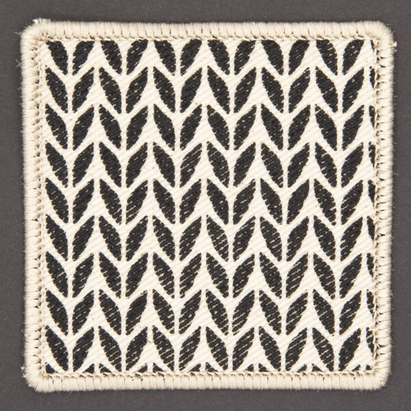 patch made from cream denim screen printed with a stocking stitch print and finished with an embroidered border