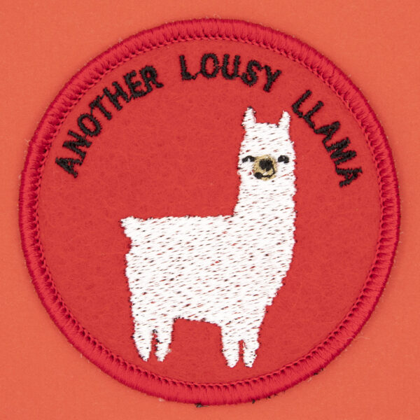 round embroidered patch picture of a white llama and text another lousy llama on red