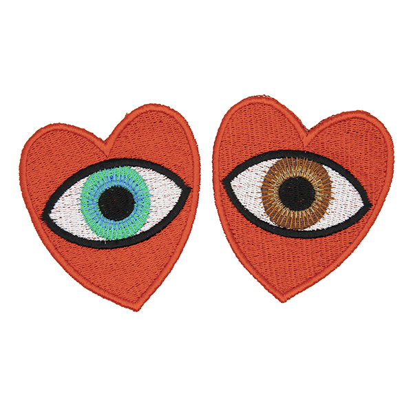 large embroidered patches , pair of red hearts, one containing a brown eye and one containing a blue eye photographed on a white background