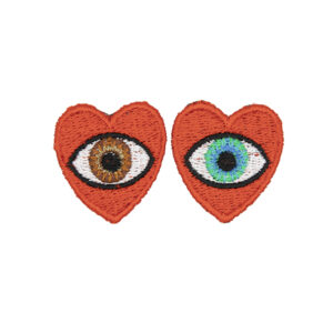 small embroidered patches , pair of red hearts, one containing a brown eye and one containing a blue eye photographed on a white background