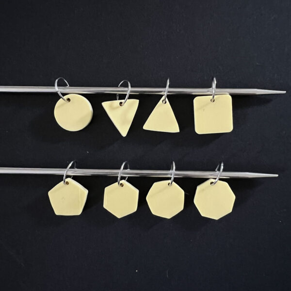 Eight geometric shapes laser cut from lemon bon bon yellow pastel perspex. Mounted on jump rings to create stitch markers.