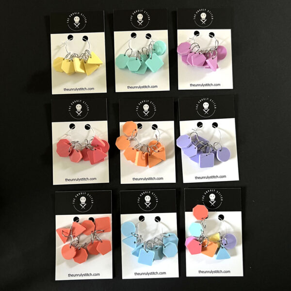 Nine colour options for geometric stich markers, all shown on The Unruly Stitch business cards. Eight sets are a single pastel colour, and the final set has a marker in eight different colours.E