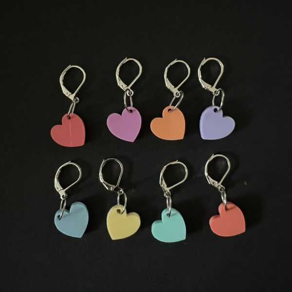 Eight hearts laser cut from eight colours of pastel perspex, . Mounted on latch back hooks to create stitch markers.