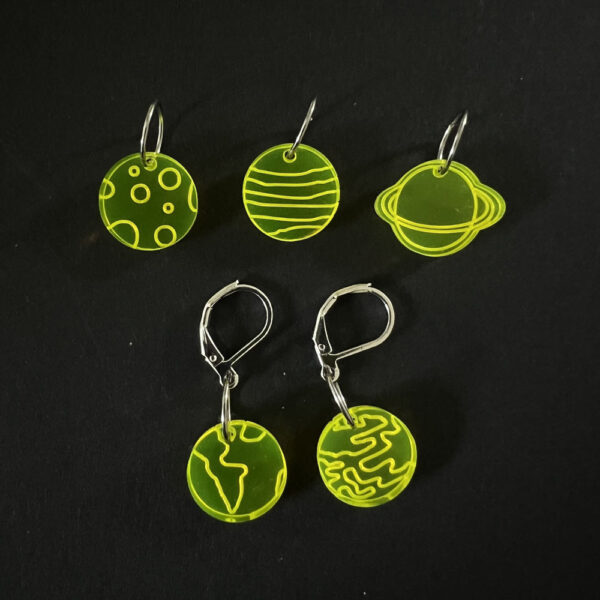 Five planets laser cut from fluorescent yellow perspex, . Mounted on a mix of jump rings and latch back hooks to create stitch markers.