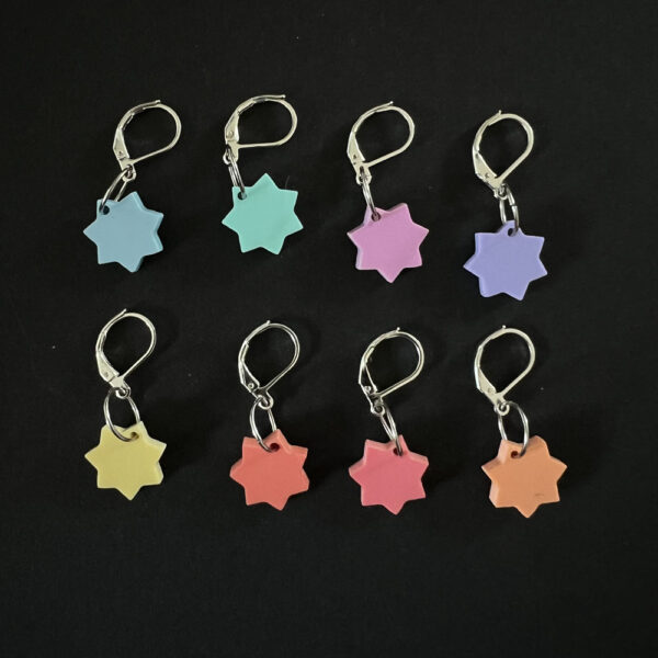 Eight stars laser cut from pastel perspex, Each star has seven points and is a different pastel colour. Mounted on latch back hooks to create stitch markers.