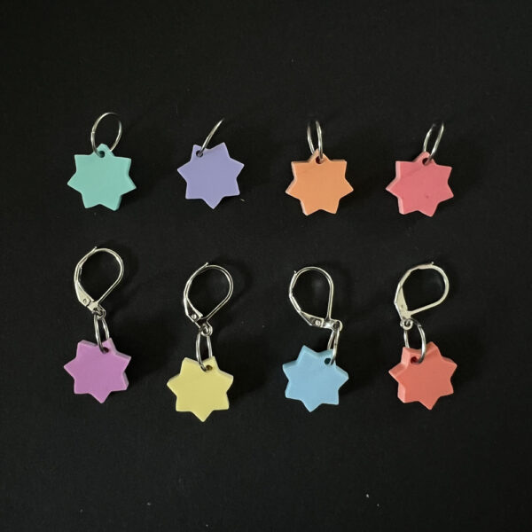 Eight stars laser cut from pastel perspex, Each star has seven points and is a different pastel colour. Mounted on a mix of jump rings and latch back hooks to create stitch markers.
