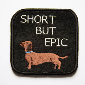 Short haired dachshund with the words short but epic embroidered patch on black felt.