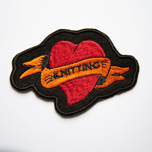 Sewing tattoo heart embroidered patch on black felt.