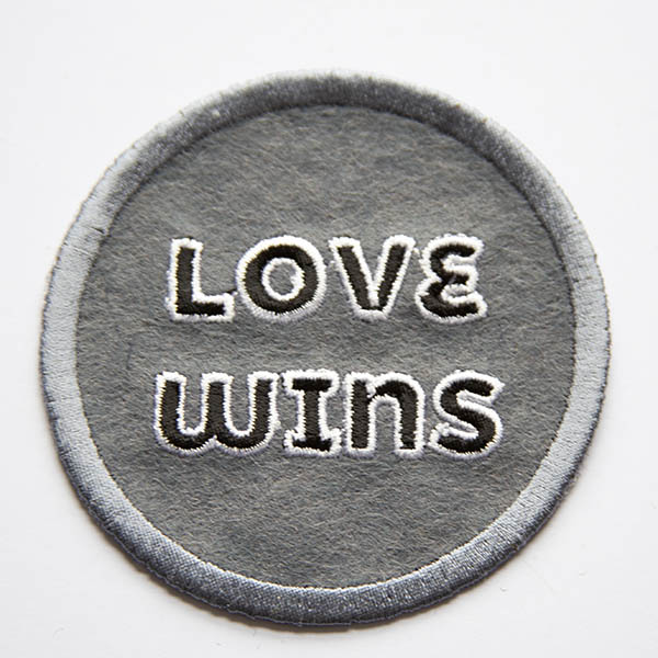 Love wins black and white patch on grey felt.