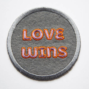 Love wins lilac and orange patch on grey felt.