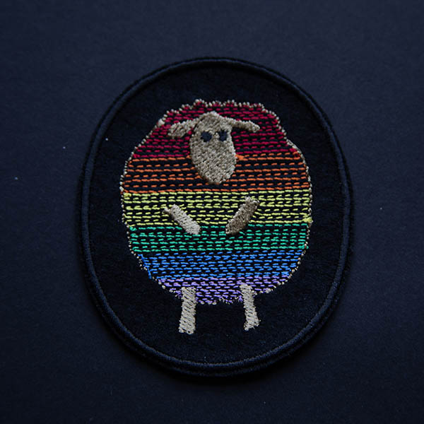 Rainbow striped sheep patch embroidered on black felt on a black background.