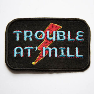 Trouble at mill overlaying lightening bolt embroidered patch on black felt.