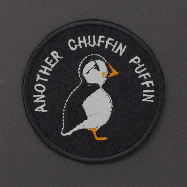 Embroidered patch on black felt showing a puffin. Text reads " ANOTHER CHUFFIN PUFFIN" . Shown on a dark background.