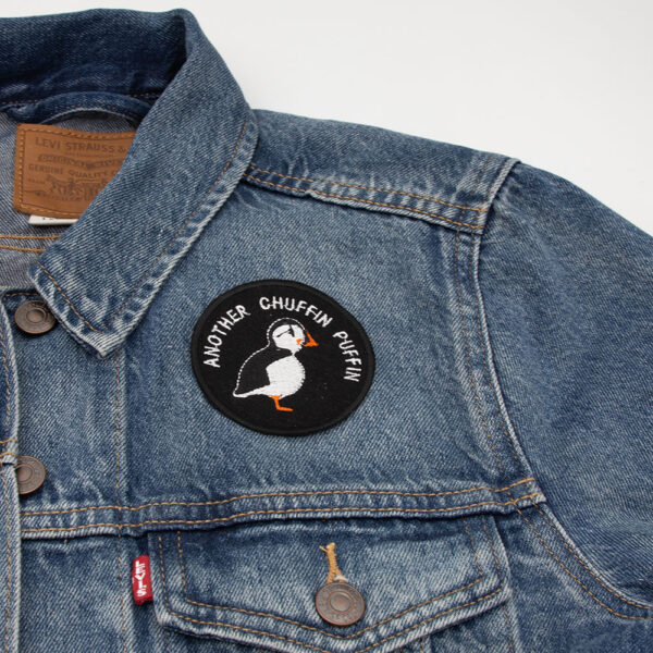 Embroidered patch on black felt showing a puffin. Text reads " ANOTHER CHUFFIN PUFFIN" . Shown on a denim jacket.