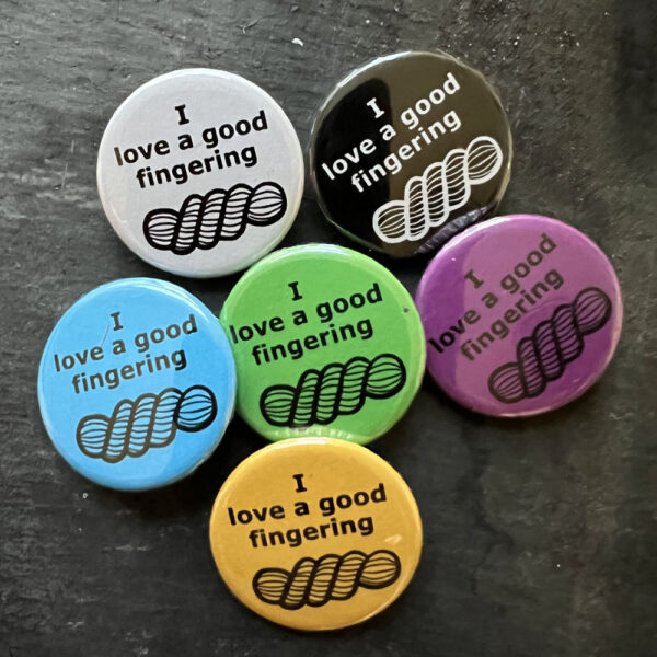 Six badges with the words I love a good fingering and line drawing of a skein of yarn. Black text on blue, yellow, green, pink and white, white text on black background.