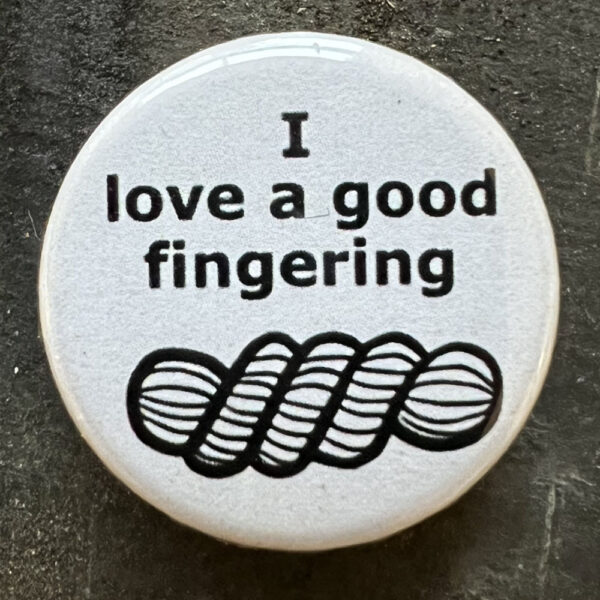 Pin badge with the words I love a good fingering and a line drawing of a skein of yarn. Black text, white background.