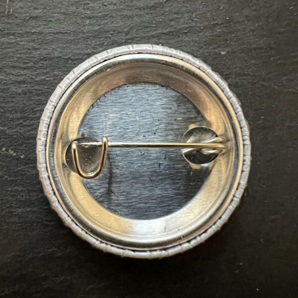 Back of pin badge showing metal of badge, pin and catch