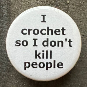 Pin badge with the words I crochet so I don't kill people. Black text, white background.