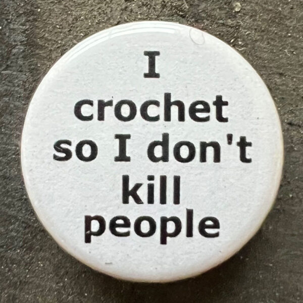 Pin badge with the words I crochet so I don't kill people. Black text, white background.