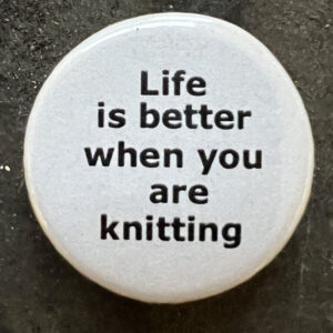 Pin badge with the words Life is better when you are knitting. Black text, white background.